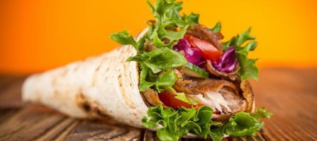 close up of kebab sandwich on wooden background